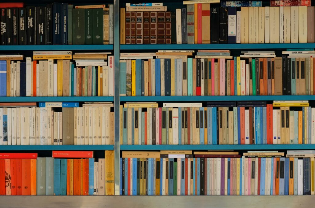 Assorted books piled on a shelf in a street bookshop, with a variety of covers