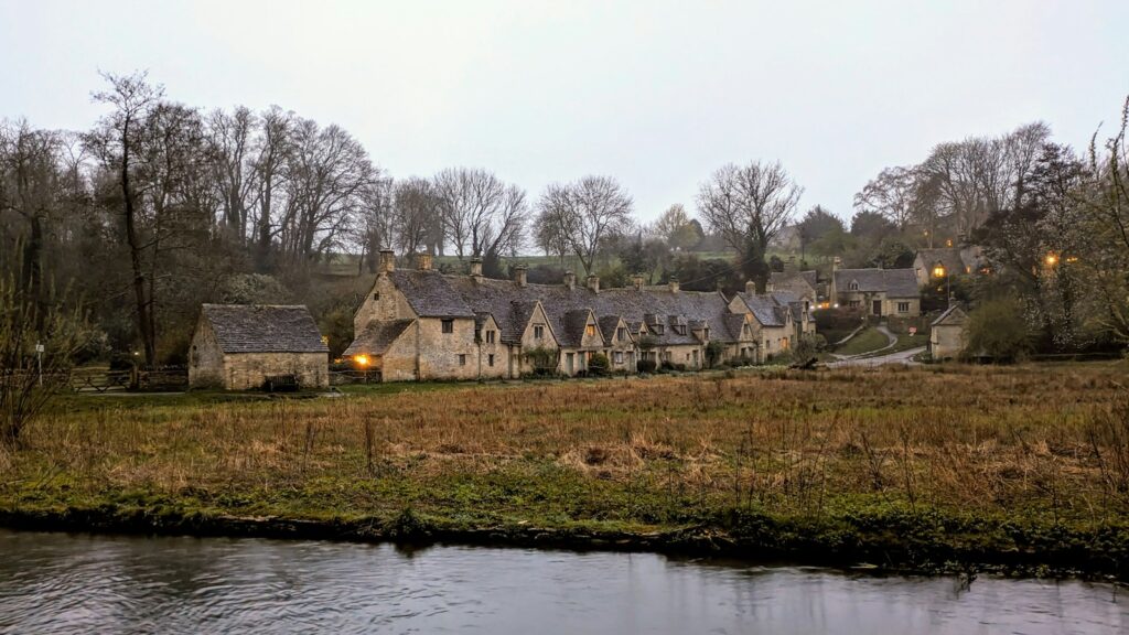 Stone cottages with gabled roofs along a river in the Cotswolds, much like those around Bibury