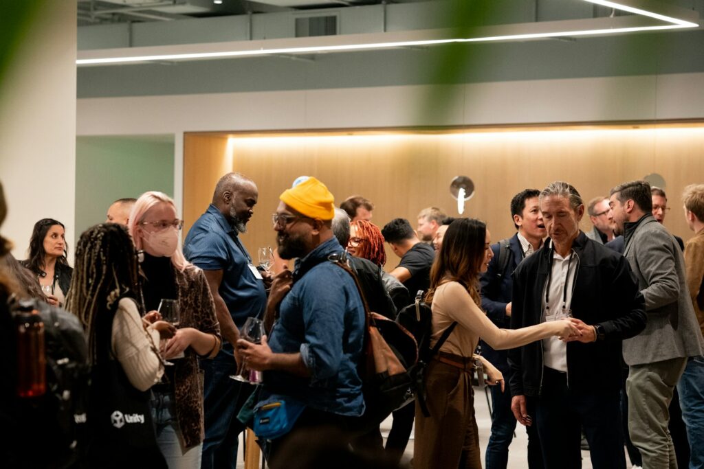 People mingling at an indoor event with warm lighting, the kind of setting for conference networking
