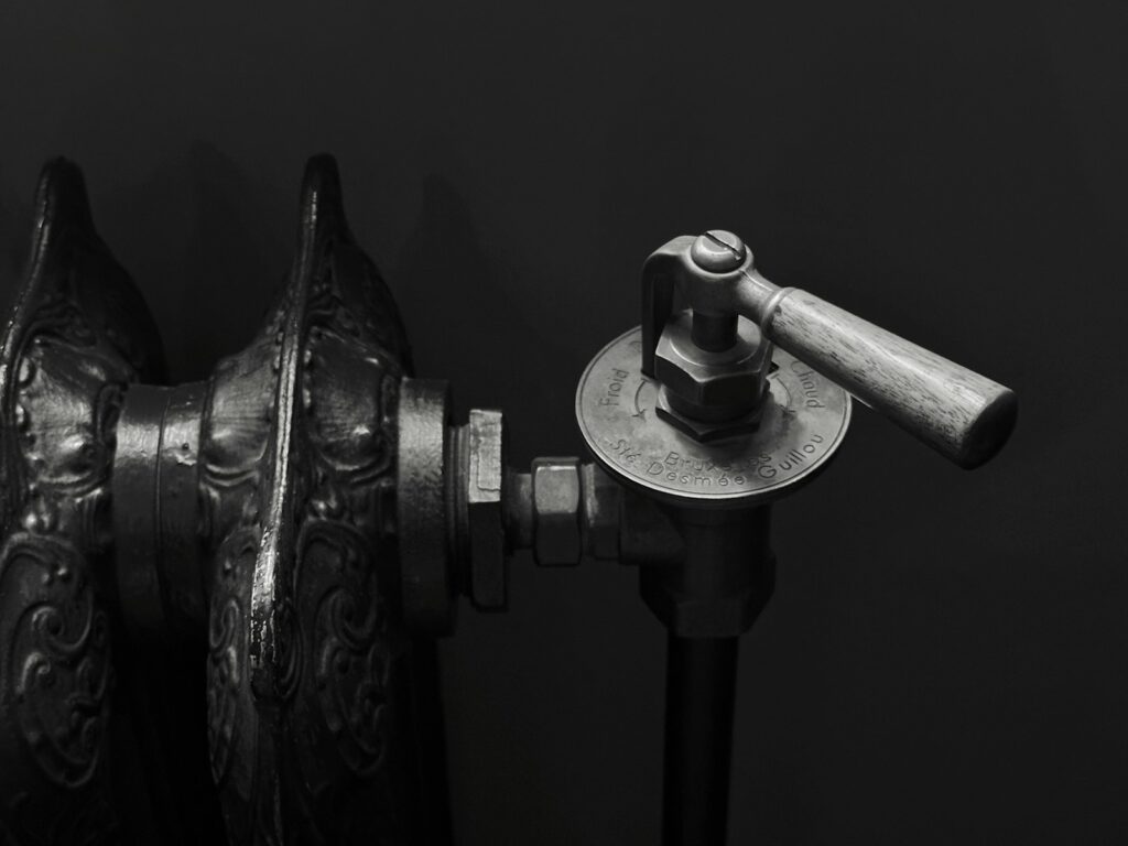 A vintage cast iron radiator with an ornate valve handle, relevant to controlling home heating costs